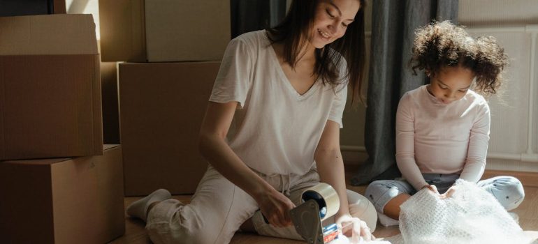 mother and daughter packing fragile items in boxes